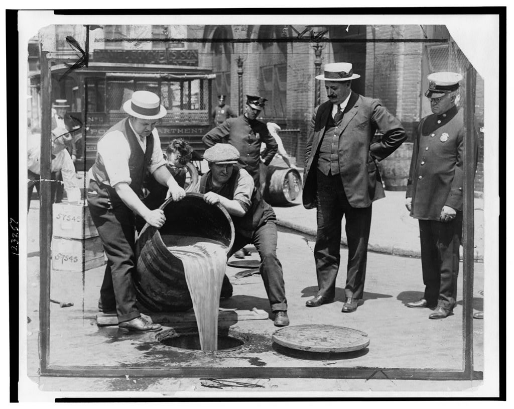 1921 police raid pours confiscated liquor into sewer during alcohol Prohibition
